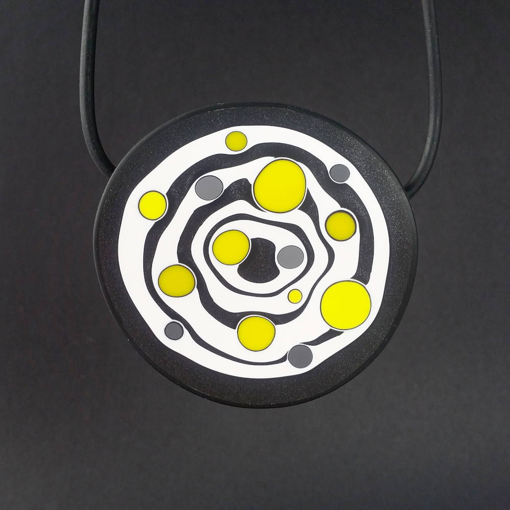 Large handmade pendant with organically-shaped concentric black and white circles, and irregular dots of bright yellow. It is approximately 6.6cm in diameter and hangs on a black adjustable cord.